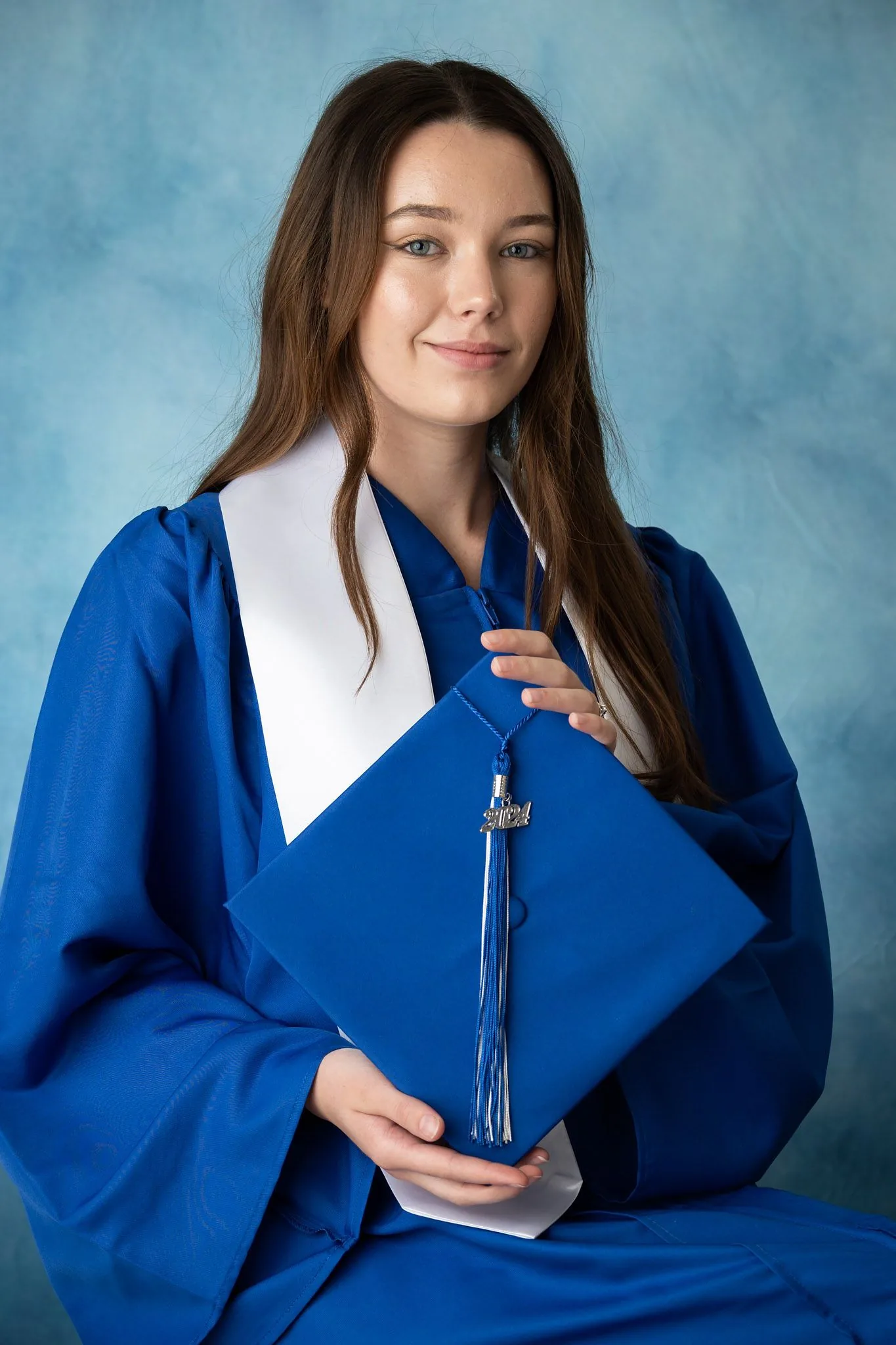 High school graduate holding a cap in a studio senior portrait